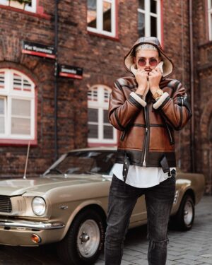 Kożuch męski w brązowym kolorze z kapturem, ozdobiony podszewką z futra i metalowymi detalami