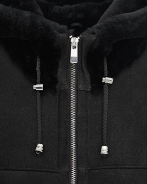 Czarny kożuch damski z kapturem i zamkiem, ozdobiony metalowymi detalami, idealny na zimowe dni